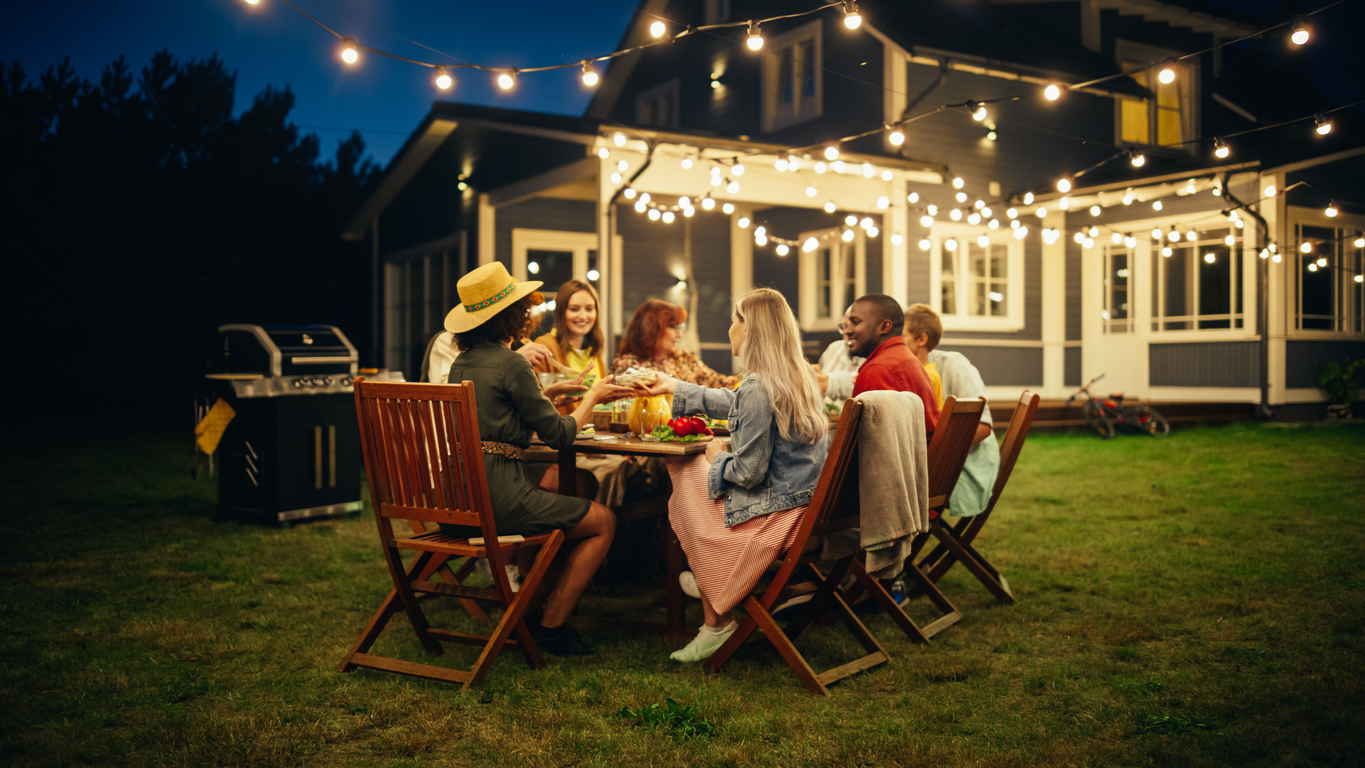 family eating outside in front of house at night